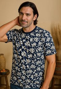 Navyblauw T-shirt met korte mouwen, voorzien van een wit bloemenpatroon. Ronde halslijn, zachte katoenen stof en een ontspannen pasvorm.