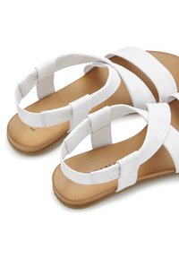 Weiße Sandalen mit einem Obermaterial aus glattem Leder, ausgestattet mit breiten Riemen und einer beigefarbenen, strukturierten Innensohle. Weiche elastische Akzente an der Ferse sorgen für Komfort.