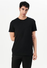 Tricou din bumbac negru cu gât rotund, mâneci scurte și o croială dreaptă. Textură netedă, design minimalist, fără modele sau accente vizibile.