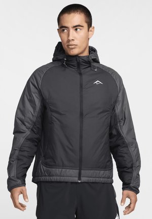Veste noire isolante avec capuche, dotée de panneaux contrastants gris, de cordons de serrage ajustables et d'une fermeture éclair à l'avant.