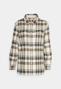 Chemise à manches longues à carreaux crème, noir et moutarde, avec fermeture boutonnée devant et deux poches poitrine à rabats et boutons.