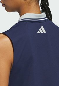 Navy sleeveless polo shirt with a gray mesh collar, featuring a white Adidas logo on the back. Smooth fabric, minimalistic design.