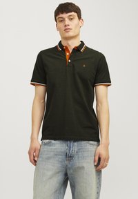 Donkergroene polo met oranje accenten op de kraag en mouwen, voorzien van een knoopsluiting en een klein logo op de borst.