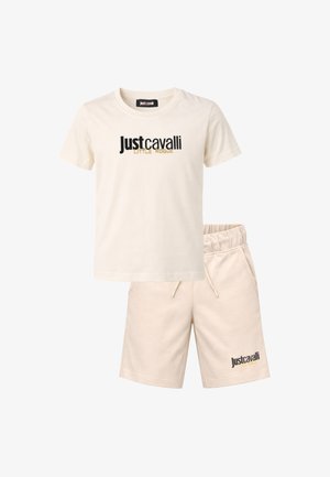 Completo con t-shirt beige a maniche corte e pantaloncini, con la stampa "Just Cavalli Little Rogue" in nero e oro su entrambi i capi.