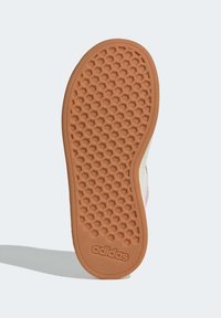 Semelle de sneaker Adidas en caoutchouc marron clair avec texture hexagonale et logo. Bords lisses et légère courbure vers la zone des orteils.
