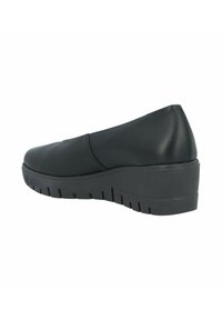 Zapato negro tipo slip-on con punta redondeada, parte superior de piel sintética suave y suela de goma gruesa y estriada con un leve tacón en cuña.