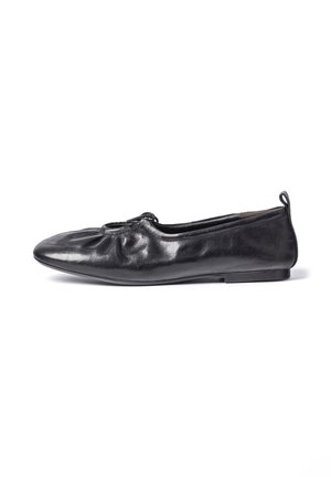 Ballerine plate en cuir noir avec dessus élastique froncé et petite languette au talon, vue de côté sur fond blanc.