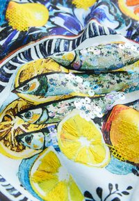 Tissu avec des imprimés détaillés de poissons et de citrons ornés de sequins irisés et de tranches de citron jaunes brodées.