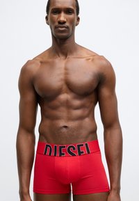 Červené bavlnené boxerky s čiernym pásom a logom "DIESEL". Priliehavý strih s hladkou textúrou bez ďalších vzorov.