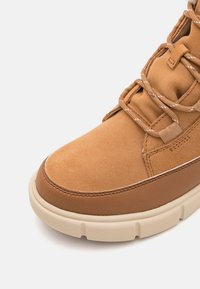 Sneaker in suede e pelle color tan con punta arrotondata, tomaia testurizzata, lacci color tan e suola in gomma beige chiaro. Cuciture decorative visibili.
