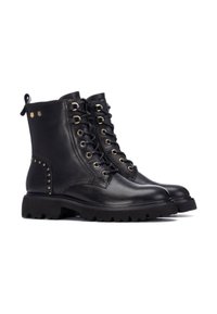Botas de tobillo de cuero negro con herrajes dorados, diseño de cordones, acentos de tachuelas en el lateral y suelas de goma gruesa para mayor agarre.