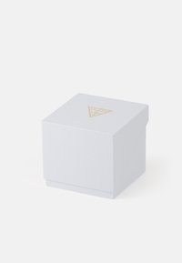 Biała kwadratowa pudełko prezentowe o teksturowanej powierzchni. Posiada złote trójkątne logo na górze. Prosty i kompaktowy design.