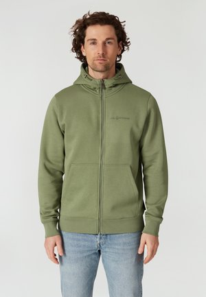 Sudadera con cremallera en color verde oliva, fabricada en un tejido suave, con capucha ajustable, bolsillos frontales y un logo discreto en el pecho.