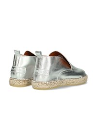 Espadrillas argentate in metallo con design aperto, suola avvolta in juta e dettagli cuciti. Presentano una piccola linguetta sul tallone per facilitare la calzata.