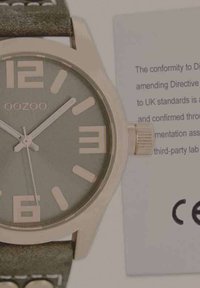 Montre analogique verte avec boîtier en or rose et grands chiffres, dotée d'un bracelet en cuir texturé. Accompagnée d'une carte de certification.