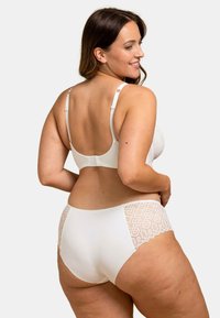 Ensemble de lingerie blanche comprenant un soutien-gorge en dentelle avec des bretelles ajustables et un slip assorti. Le slip présente un accent en dentelle à motifs sur les côtés.