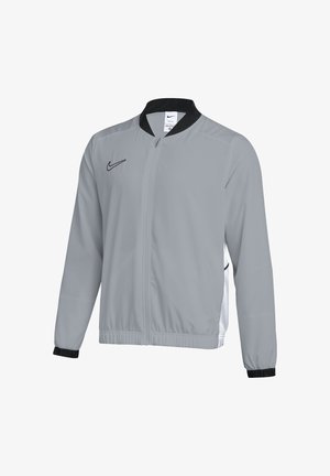 Graue Nike Zip-Up Jacke mit schwarzem Kragen und Bündchen, langen Ärmeln und schwarzem Nike-Logo auf der Brust und seitlichen Mesh-Einsätzen.