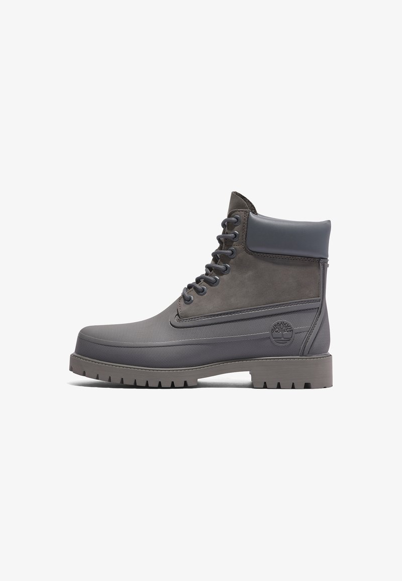 Bottine grise imperméable à lacets, col rembourré et semelle robuste, logo Timberland embossé sur le côté.