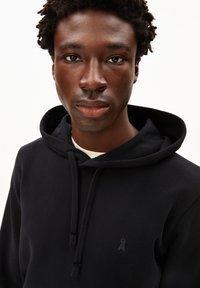 Felpa con cappuccio nera realizzata in morbido tessuto, con tasca frontale e un piccolo logo sul petto. Texture liscia con cappuccio regolabile.