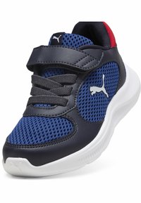 Sneaker bleu marine et mesh avec une tige supérieure noire solide et durable, des lacets gris, une semelle blanche et un accent rouge au talon. Présente un logo Puma.
