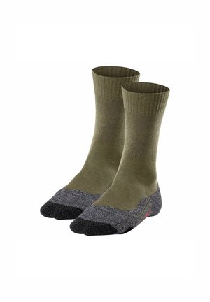 Calcetines verde oliva con un ribete en el tobillo, presentando una puntera y un talón texturizados en gris. El diseño distintivo incluye un acento de logo rojo.