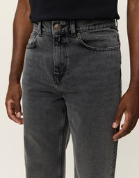 Tumši pelēki denima džinsi ar augsto jostasvietu, klasisku piecu kabatu stilu un metāla pogu aizdari jostasvietā.