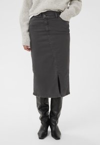 Sivá denim midi sukňa s predným rozparkom, štruktúrovaný strih, pútka na opasok a kontrastné švy. Nosí sa s vysokými čiernymi koženými čižmami.