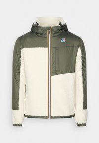 Grüne und cremefarbene Jacke mit Kapuze, gestepptem Stoff, flauschiger Textur, durchgehendem Reißverschluss vorne und kontrastierenden gelben Reißverschlussakzenten.