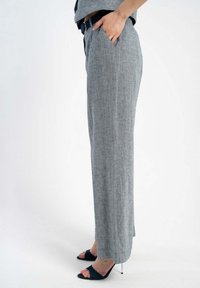 Szare lniane spodnie o prostym kroju, z bocznymi kieszeniami i mankietami. Połączone z granatowymi sandałami na obcasie, które prezentują elegancki design i teksturę.