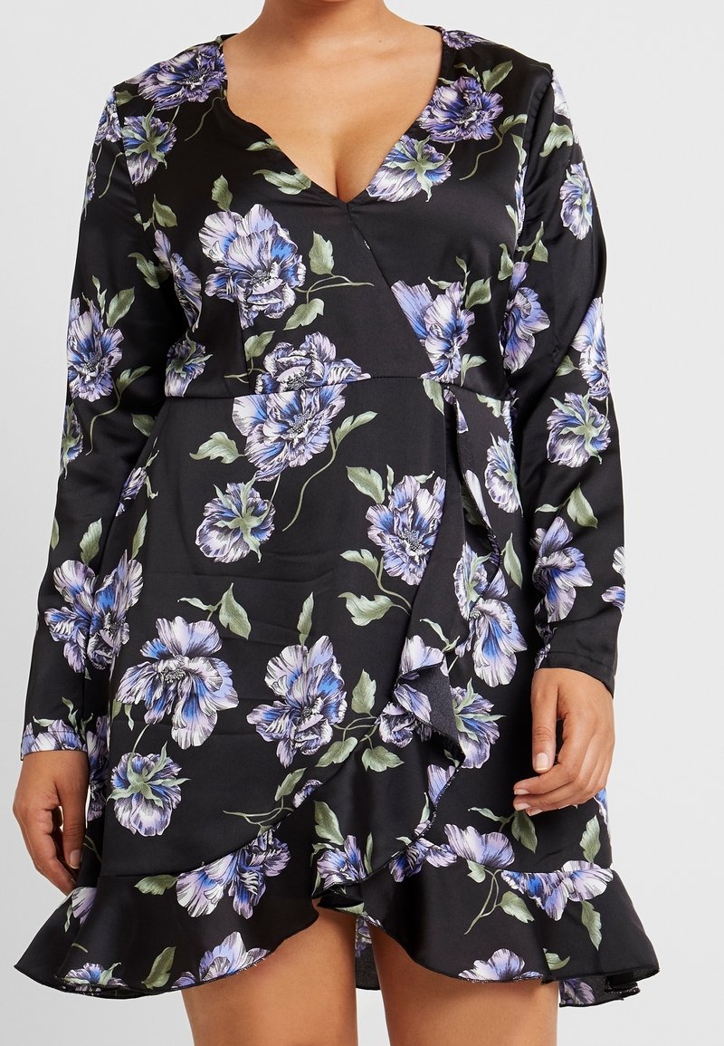 Svart blommig klänning med långa ärmar, V-ringning, volangkant och ett mönster av lila och gröna blommor på ett mjukt tyg.