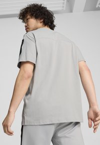 Vaaleanharmaa lyhythihainen t-paita pehmeästä kankaasta, jossa on rento istuvuus ja erottuva musta yksityiskohta hartioilla.