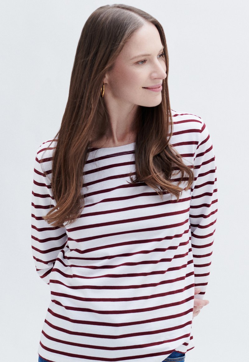 Raidallinen pitkähihaiste paita valkoisena ja burgundin värisenä, jossa on veneen muodossa kaula-aukko, rento malli ja pehmeä kangas, jossa on hieno tekstuuri.