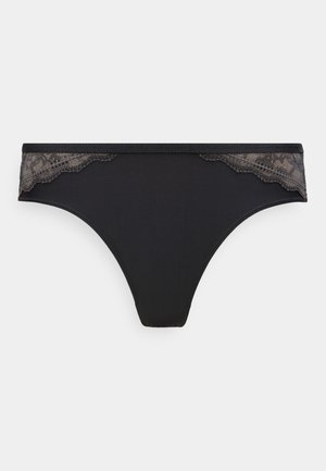 Mutande bikini da donna nere con bordo in pizzo lungo la fascia in vita su entrambi i lati, su sfondo semplice.