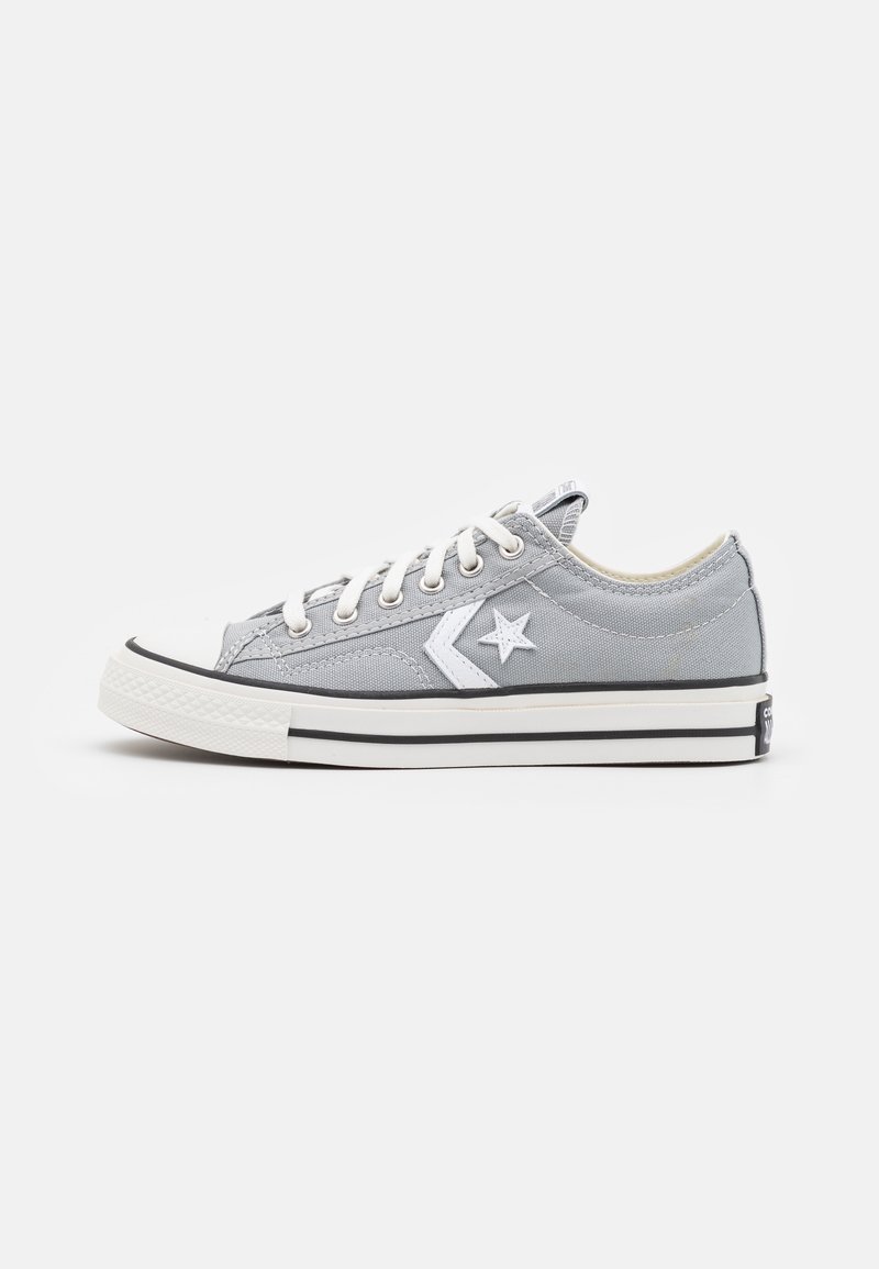 Baskets basses en toile grise avec des lacets blancs, un logo d'étoile blanche sur le côté et une semelle en caoutchouc blanche avec des rayures noires.