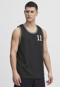 Sort ærmeløs basketballtrøje med hvidt nummer 11. Har en mesh-struktur og kontrasterende hvide kanter på halsudskæringen.