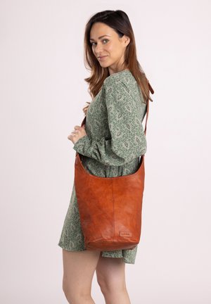 Borsa a spalla in pelle marrone con un design morbido, dotata di una sola tracolla e una superficie texture. Accentuata con un'etichetta della marca.