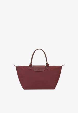 Medium-sized maroon tote bag with leather handles, leather flap, and silver zipper closure, designed for casual or travel use.