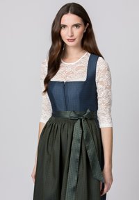 Traditional dirndl featuring a fitted navy bodice with lace sleeves, a green pleated skirt, and a satin bow at the waist.