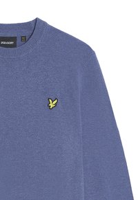 Maglione azzurro lavorato a maglia con scollo a girocollo, caratterizzato da un piccolo logo di un uccello giallo e nero sul petto sinistro. Texture morbida e design informale.