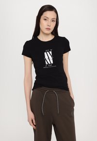 Svart bomull t-skjorte med et sentralt hvitt grafisk logo. Designet inkluderer teksten "ARMANI EXCHANGE" og et geometrisk mønster.