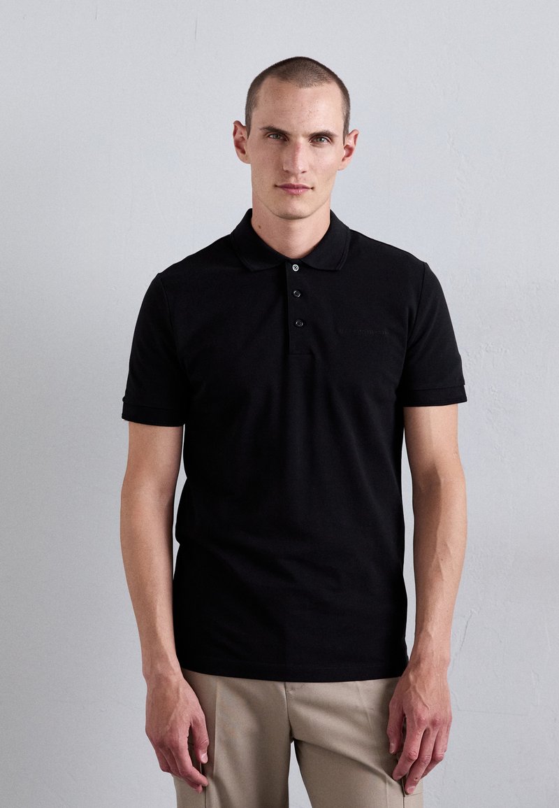 Svart polo skjorte laget av bomull, med krage, tre-knappes placket, og korte ermer. Glatt tekstur uten synlige mønstre.