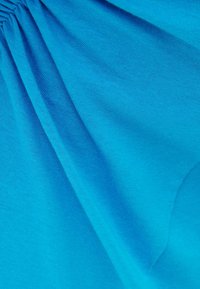 Jasnoniebieska tkanina o gładkiej strukturze, z miękkimi fałdami i marszczeniami, które tworzą delikatne układanie.