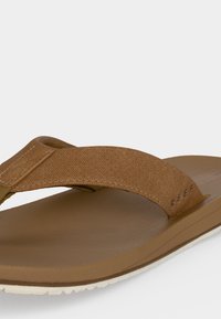 Καφέ σαγιονάρα με υφή στην σόλα και υφασμάτινο λουράκι με ενισχυμένες ραφές σε λευκό φόντο.