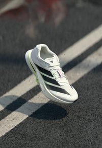 Sport shoe with a lightweight, white mesh upper, black striped design, pastel accents, and a cushioned sole for enhanced performance.