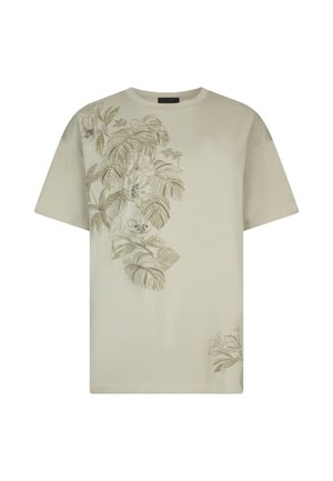 Beżowy t-shirt z krótkim rękawem z botanicznym nadrukiem przedstawiającym duże liście i kwiaty ozdobione małymi cyrkoniami po lewej stronie przodu.