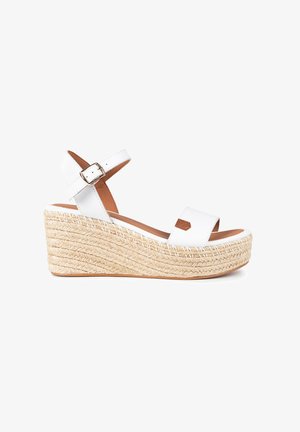 Sandalia de cuña blanca con suela de yute trenzada, dos correas anchas, correa de tobillo ajustable y textura suave y mate.