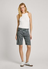Hallide hallid denim shorts viie-taskulise disainiga, nupukinnise ja rullitud servaga. Koos valge breziga ja valgete jooksujalatsitega.