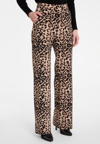 Beige en zwarte broek met luipaardprint, met een hoge taille, zakken en een gladde textuur. Te combineren met zwarte hakken.