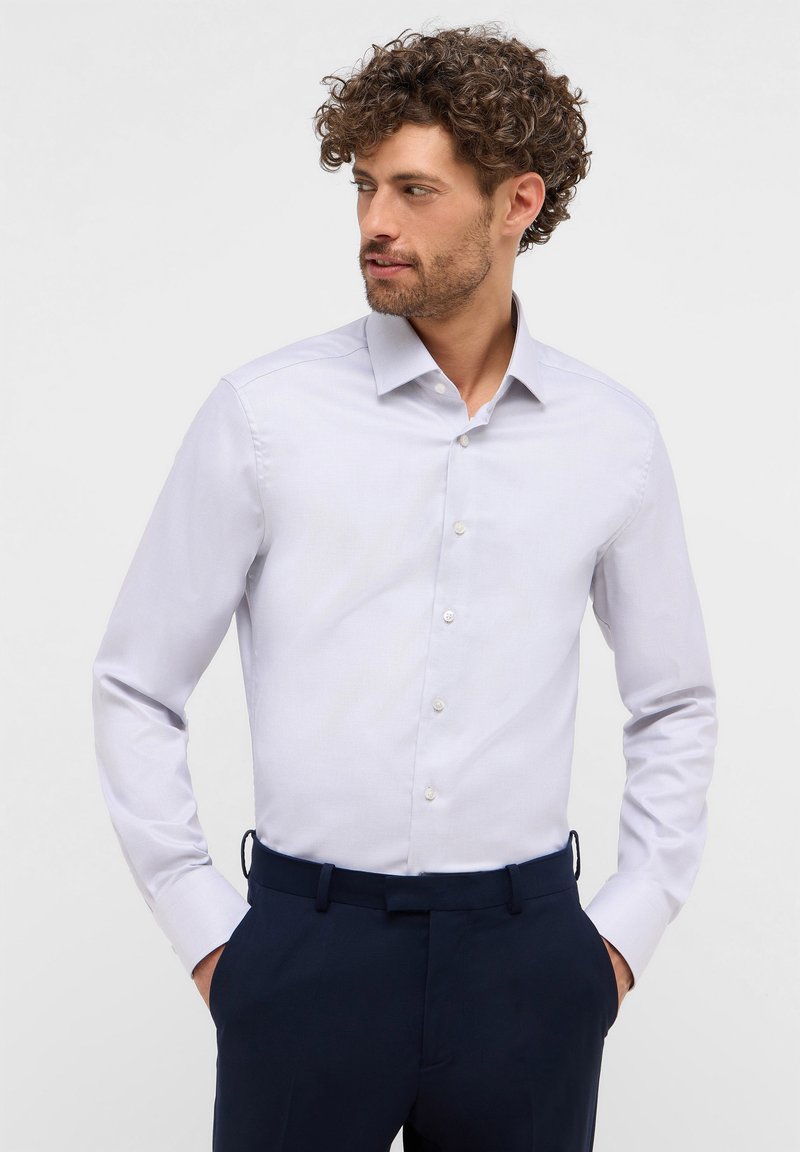 Camicia a maniche lunghe azzurro chiaro con chiusura a bottoni, realizzata in tessuto liscio. Presenta un colletto classico e una trama sottile.