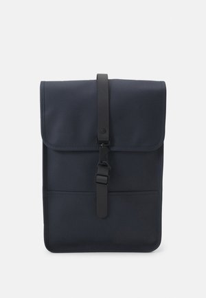 Navy backpack with a fold-over flap, featuring a black buckle closure and a front pocket. Made of durable material with smooth texture.